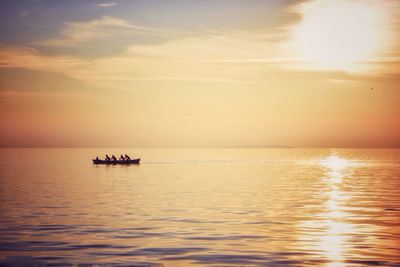 Scenic view of sea against sky during sunset with silhouette of canoe