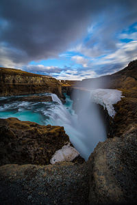 Scenic view of waterfall against sky