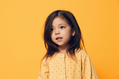 Portrait of young woman against yellow background