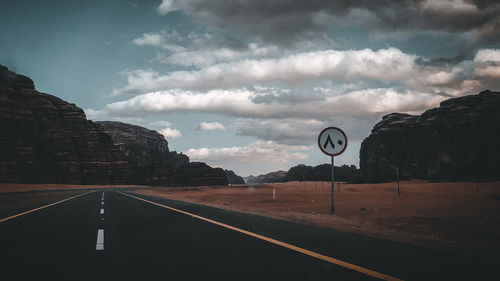 Road sign by mountain against sky