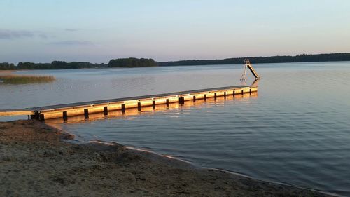 Pier on lake against sky during sunset