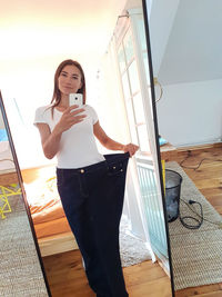 Young woman using mobile phone while standing on floor