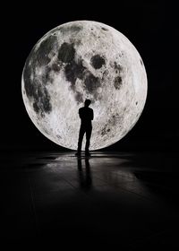 Silhouette man standing against moon at night