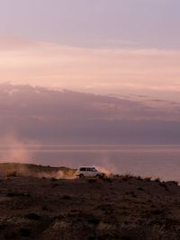 Vehicle on field against sky during sunset