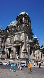 Group of people in front of historic building against clear sky