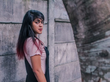 Portrait of beautiful woman standing against wall