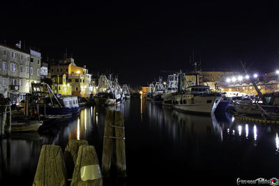 Boats moored at harbor in city at night