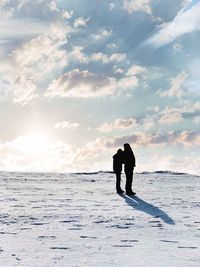 Silhouette man standing by sea against sky during winter