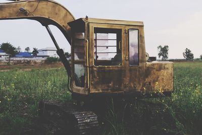 Abandoned car on field against sky