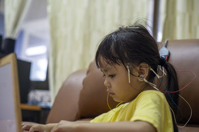 Cute girls with electrodes on head sitting on sofa