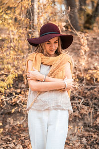 Young woman wearing hat standing by tree