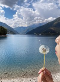 Girl blows the dandelion ,view lake and mountains.