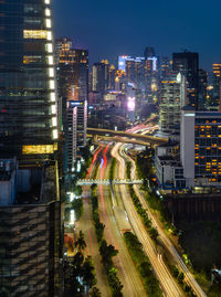 High angle view of light trails on road amidst buildings in city
