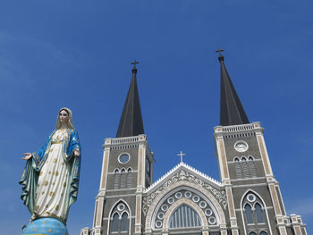 Low angle view of statue against building against clear blue sky