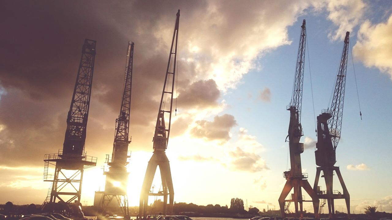 sky, sunset, cloud - sky, low angle view, construction site, built structure, industry, crane - construction machinery, development, silhouette, architecture, cloudy, tall - high, cloud, outdoors, metal, orange color, construction industry, sunlight, crane