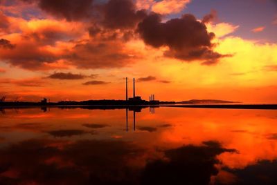 Scenic view of lake against cloudy sky at sunset