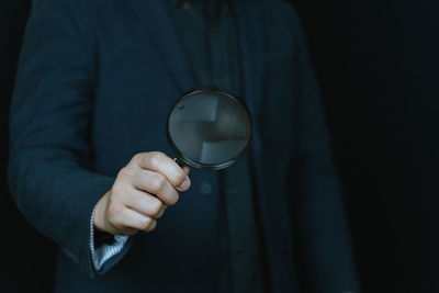 Midsection of man holding magnifying glass
