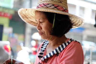 Close-up of mature woman wearing hat outdoors