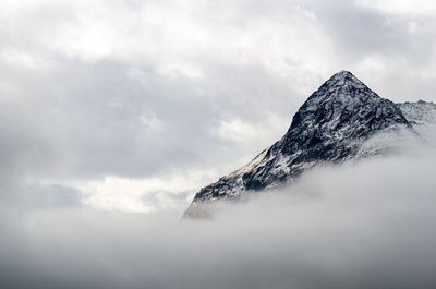 High section of rocky mountain against clouds