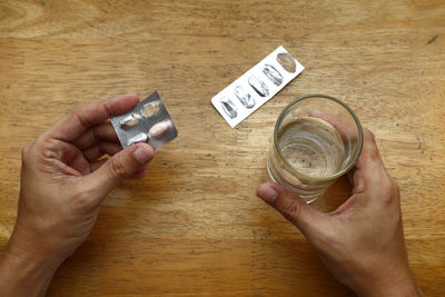 High angle view of hand holding coffee cup on table