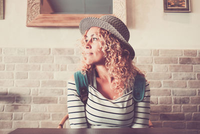 Portrait of woman wearing hat against brick wall