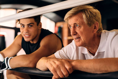 Coach talking with boxer by railing in sports ring