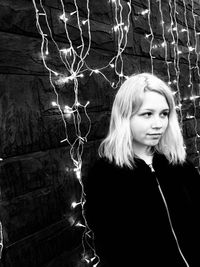 Young woman standing amidst illuminated lights