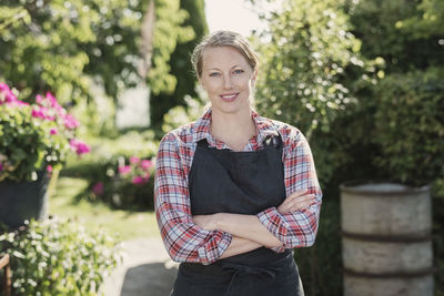 Portrait of confident woman with arms crossed standing in garden