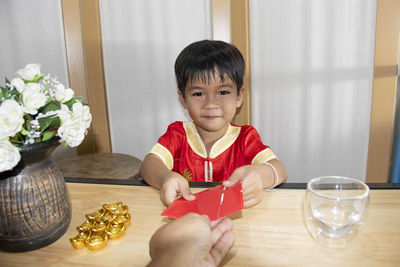 Portrait of boy sitting on table at home