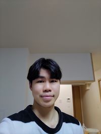 Portrait of smiling young man against wall at home