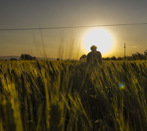 Farmer standing on field against sky during sunset