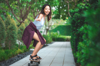 Portrait of smiling woman standing on footpath