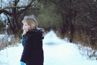 Rear view of girl standing in snow