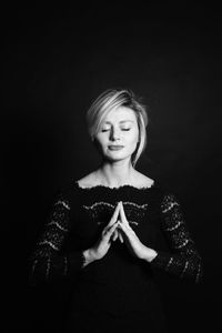 Young woman with eyes closed against black background