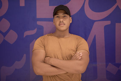 Portrait of young man standing against wall