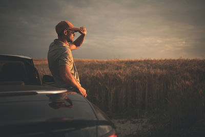 Man photographing car on field against sky