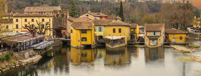 Wide high angle view of valeggio sul mincio with the buildings reflecting on the water at sunset