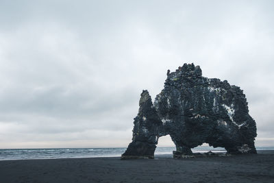 Rock formation on beach against sky