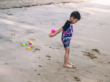 Full length of boy holding toy at beach