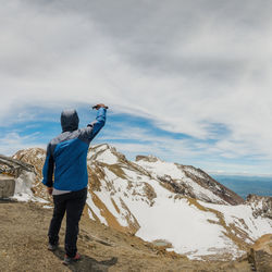 Rear view of man standing on mountain against sky