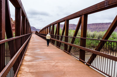 Footbridge leading towards bridge against sky