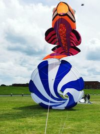 Multi colored balloons on field against sky