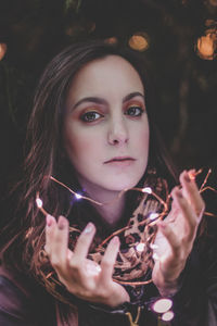Close-up portrait of beautiful woman holding illuminated lights