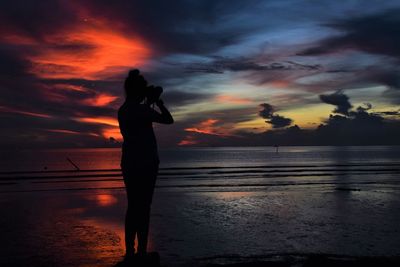 Silhouette woman standing at beach during sunset