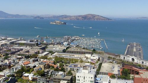 High angle view of city by sea against sky