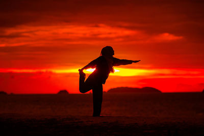 Silhouette woman standing on field against sky during sunset