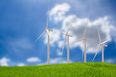 Wind turbines on field against sky