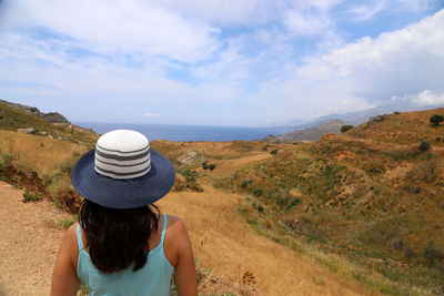 Rear view of woman in hat at beach against sky