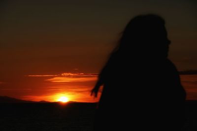 Silhouette woman standing by sea against sky during sunset