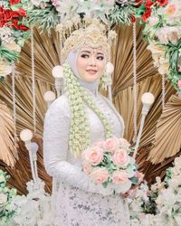 Portrait of woman with pink flowers against wall